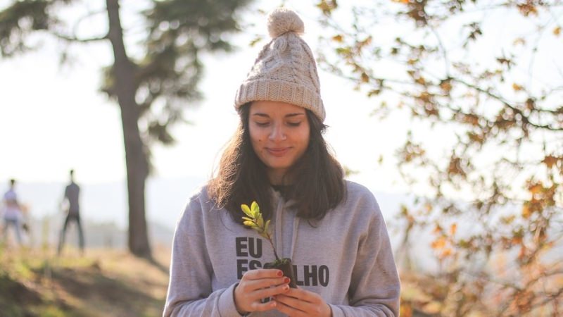 Jovem com pequena árvore na mão